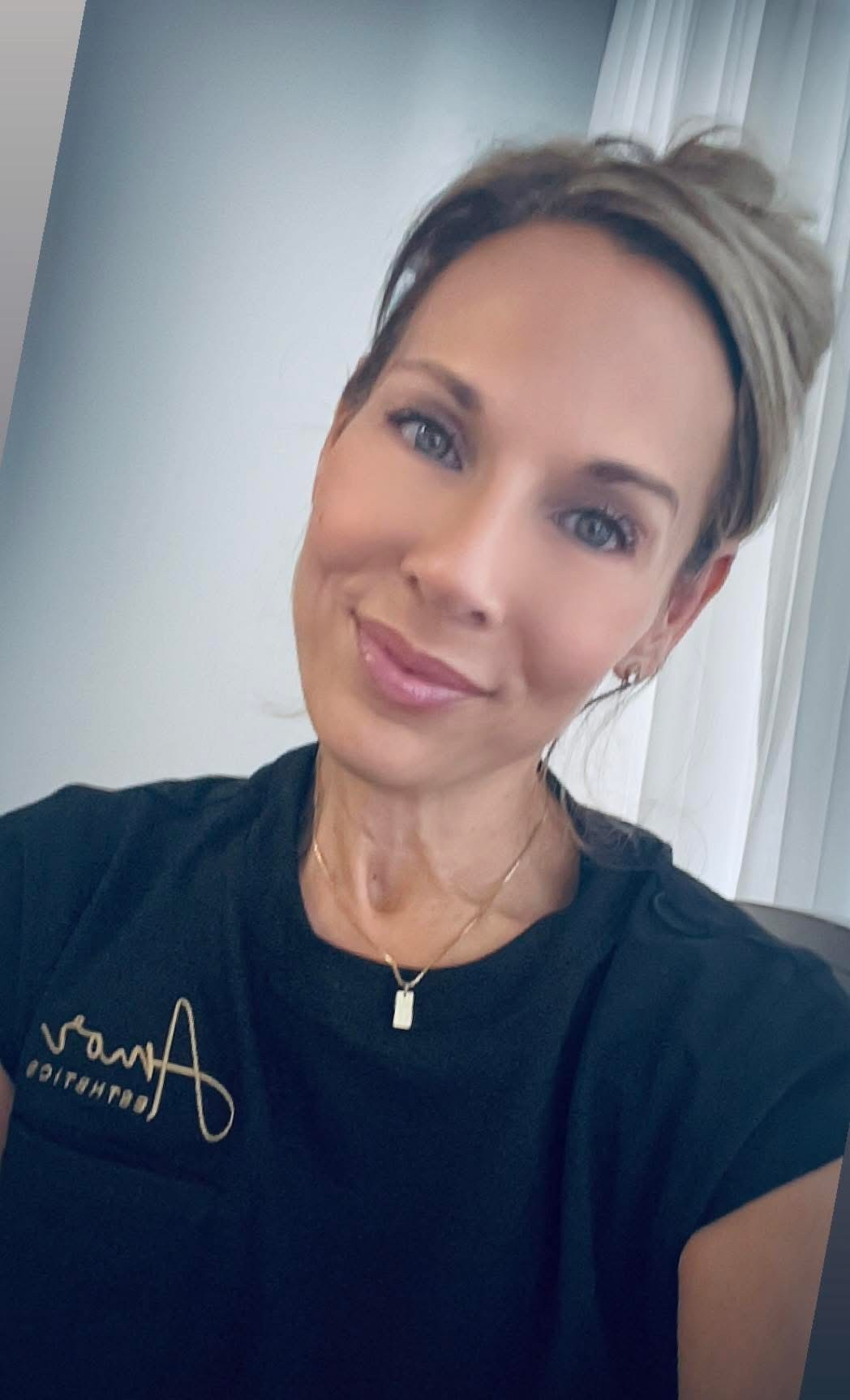 Lori, the solo esthetician and owner of Amor Esthetics, wearing a black Amor Esthetics tee